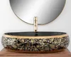 A close-up shot of a decorative washbasin with a gold faucet, set against a white background and a round mirror. Produktbild-Vorschau