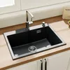 A black kitchen sink with a chrome faucet and soap dispenser is installed on a wooden countertop. Produktbild-Vorschau