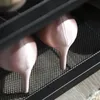 A close-up view of two pink high heels on a black metal shelf. Produktbild-Vorschau