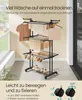 A multi-tiered drying rack with clothes and shoes on it, set up indoors near a window. Produktbild-Vorschau