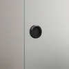 A close-up of a black circular handle on a glass sliding door. Produktbild-Vorschau