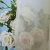 A close-up view of white roses partially obscured by a sheer, beige curtain. Produktbild-Vorschau