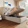 A bed with its storage compartment open, revealing the mattress and bedding. The room has wooden floors and a large window. Produktbild-Vorschau