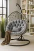 A hanging chair with a cushion and a blanket in a room with a bookshelf and a window. Voir les images du produit