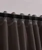 A close-up view of the top of dark gray curtains hanging from a black curtain rod. Produktbild-Vorschau