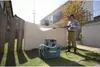 A man is using a pressure washer in a backyard setting. Náhled obrázku produktu