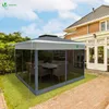 A grey gazebo with mesh sides is set up on a lawn next to a brick patio and a house. Voir les images du produit