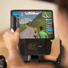 A person using an exercise bike with a tablet displaying a virtual cycling simulation. Podgląd zdjęcia produktu