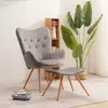 A grey armchair and ottoman are placed on a rug in a room with a plant and a small bookshelf. Náhľad obrázku produktu
