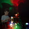 A young boy is playing with a glowing magnetic marble run in a dark room, with colorful lights and shadows projected on the wall. Náhled obrázku produktu