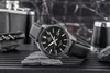 A watch is displayed on rocks with a flask and a corkscrew in the background. Voir les images du produit