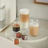 A coffee machine with three glasses of coffee and coffee capsules on a marble tray. Produktbild-Vorschau