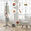 A gray wooden coat rack with items like clothes, a scarf, a hat, a handbag, a tie, and an umbrella displayed in circular graphics around it. The coat rack is in a room with a white armchair and a vase of tulips. Produktbild-Vorschau