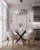 A dining room setting with a glass-top table and chairs, a chandelier, and wall sconces. Produktbild-Vorschau