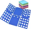 A blue folding board for clothes is laid out flat, with a stack of folded colorful t-shirts in the upper right corner. Náhled obrázku produktu