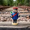 Ein Räuchermann in einer blauen Uniform mit roter Mütze steht auf Bahnschienen und hält eine grüne Kelle sowie eine Pfeife in den Händen umgeben von einer grünen Waldlandschaft Produktbild-Vorschau