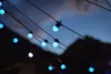 String lights are strung across a dark sky with clouds and mountains in the background. Náhled obrázku produktu