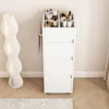 A white standing cosmetics rack filled with various bottles and containers, placed next to a decorative floor lamp. Produktbild-Vorschau