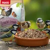 Several small birds are gathered around a bowl of birdseed, with a bag of birdseed in the background. Produktbild-Vorschau