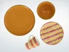 A collection of orange and patterned tableware items, including plates, a bowl, and a mug, arranged on a white background. Náhľad obrázku produktu
