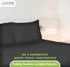 A close-up view of a dark gray bed sheet and pillowcase set on a bed, with a bedside lamp and wall light in the background. Produktbild-Vorschau