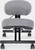 A gray kneeling chair with a black metal frame and wheels, shown from the front. Produktbild-Vorschau