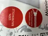 Close-up of two red circular labels with German text and graphics on a light gray and white patterned background. Produktbild-Vorschau