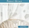 A close-up view of sheer white curtains with a cloud pattern, draped over a light-colored wicker furniture piece. Produktbild-Vorschau