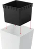 A black planter insert is shown being lowered into a white planter. Red arrows indicate the direction of movement. Náhľad obrázku produktu