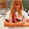 A woman is holding several bottles of hair products outdoors. Podgląd zdjęcia produktu