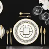 A formal table setting with plates, cutlery, and glasses on a black tablecloth. Voir les images du produit