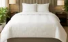 A white comforter and two pillows are neatly arranged on a bed with a tufted headboard. Produktbild-Vorschau