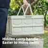 A person is holding a folded camping box outdoors. Produktbild-Vorschau
