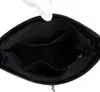 The inside of a black handbag is shown, with a hand wearing a white glove holding the top edge. Náhľad obrázku produktu