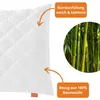 A close-up of a white quilted pillow with orange text boxes and a circular image of bamboo stalks. Produktbild-Vorschau