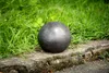 A single gray garden ball sits on a concrete curb next to green grass. Anteprima dell’immagine prodotto