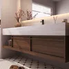 A modern bathroom vanity with a stone countertop, wooden drawers, and a black faucet, illuminated by soft lighting. Produktbild-Vorschau