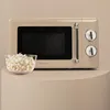 A retro-style beige microwave oven is shown on a pedestal with a bowl of popcorn in front of it. Produktbild-Vorschau