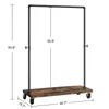A garment rack with a wooden shelf and wheels, shown with dimensions marked. The rack is made of black metal pipes. Náhled obrázku produktu
