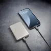 A smartphone is being charged by a power bank on a dark textured surface. Voir les images du produit