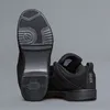 A pair of black shoes shown from a low angle against a gray background. Podgląd zdjęcia produktu