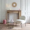 A cozy living room scene with a boucle armchair, a rustic fireplace, and decorative elements. Voir les images du produit