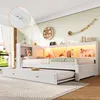 A white daybed with a pull-out trundle bed is set up in a child's bedroom, illuminated by warm LED lighting. Voir les images du produit