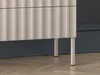 Close-up of the bottom part of a sideboard with ribbed fronts and legs, placed on a wooden floor in front of a dark blue wall. Produktbild-Vorschau