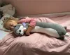 A young child sleeping in bed, hugging a long plush dog toy. Voir les images du produit