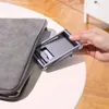 A hand is shown placing a gray foldable phone stand into a gray laptop sleeve. Náhľad obrázku produktu