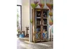 A colorful, rustic wooden display cabinet filled with books and decorative items, placed in a room with a patterned wallpaper and a chair and table visible in the background. Anteprima dell’immagine prodotto