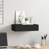 A black floating shelf mounted on a white wall, decorated with a framed picture of leaves, a small potted cactus, and a set of reed diffusers. Below the shelf, on a wooden desk, is an open book, a laptop, and a cup of coffee. Produktbild-Vorschau