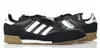 A pair of black Adidas Mundial Goal soccer shoes with white stripes and tan soles are displayed against a white background. Anteprima dell’immagine prodotto
