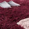 A close-up view of a fluffy rug with a pair of gray slippers on it. Produktbild-Vorschau